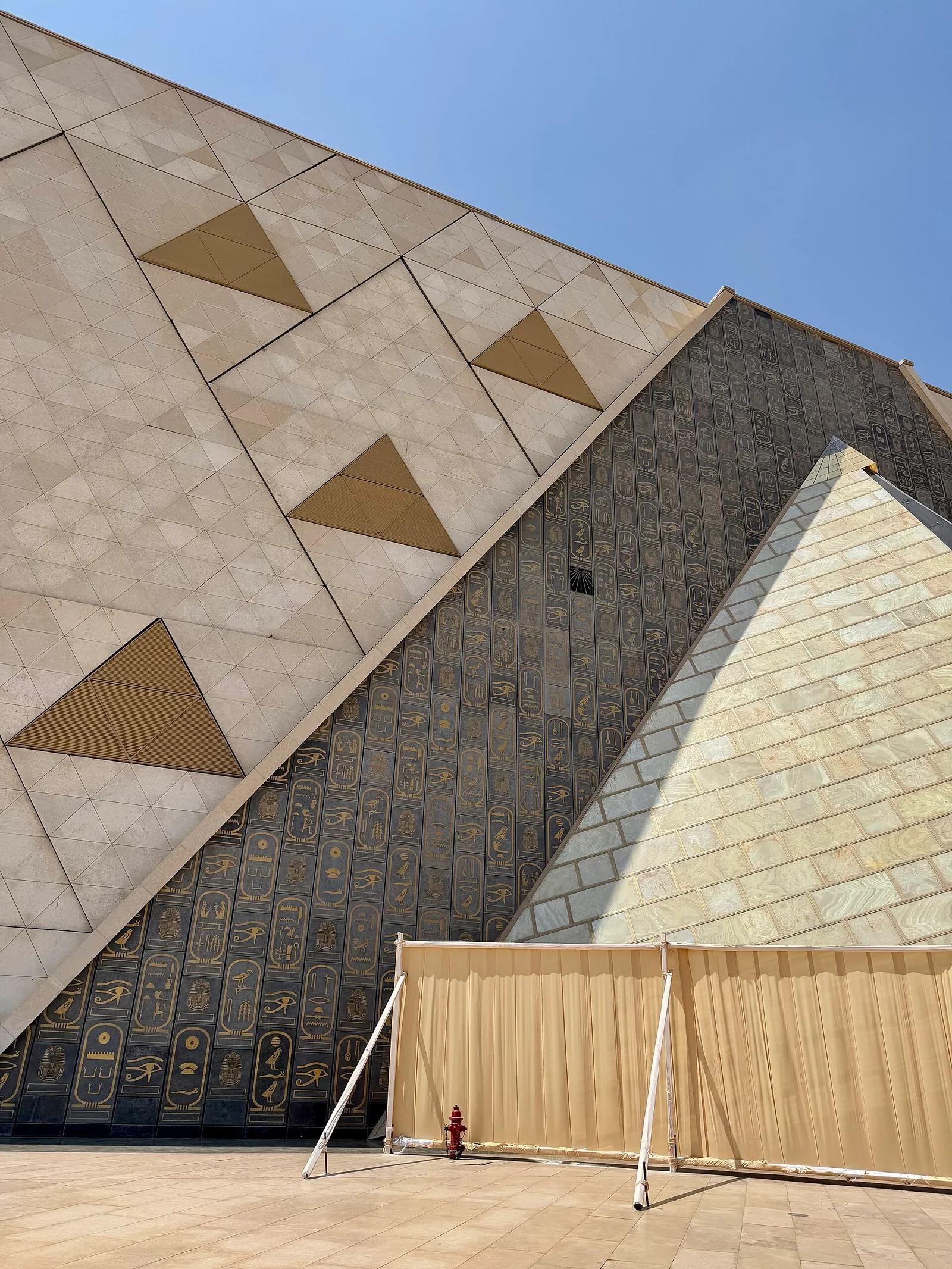 A monumental stone facade cut with triangular apertures in bright desert light.
