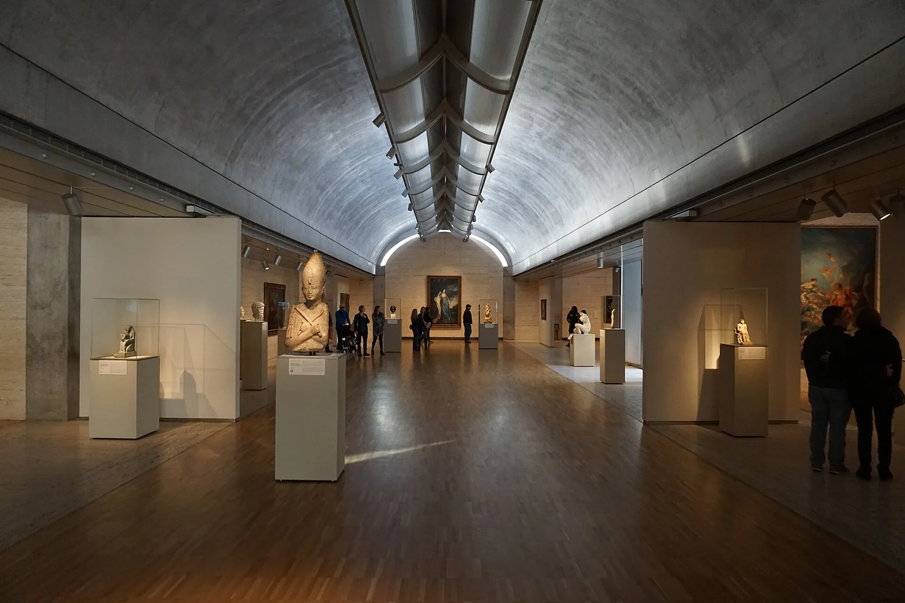 A vaulted concrete gallery lit by a narrow band of daylight along the ceiling.