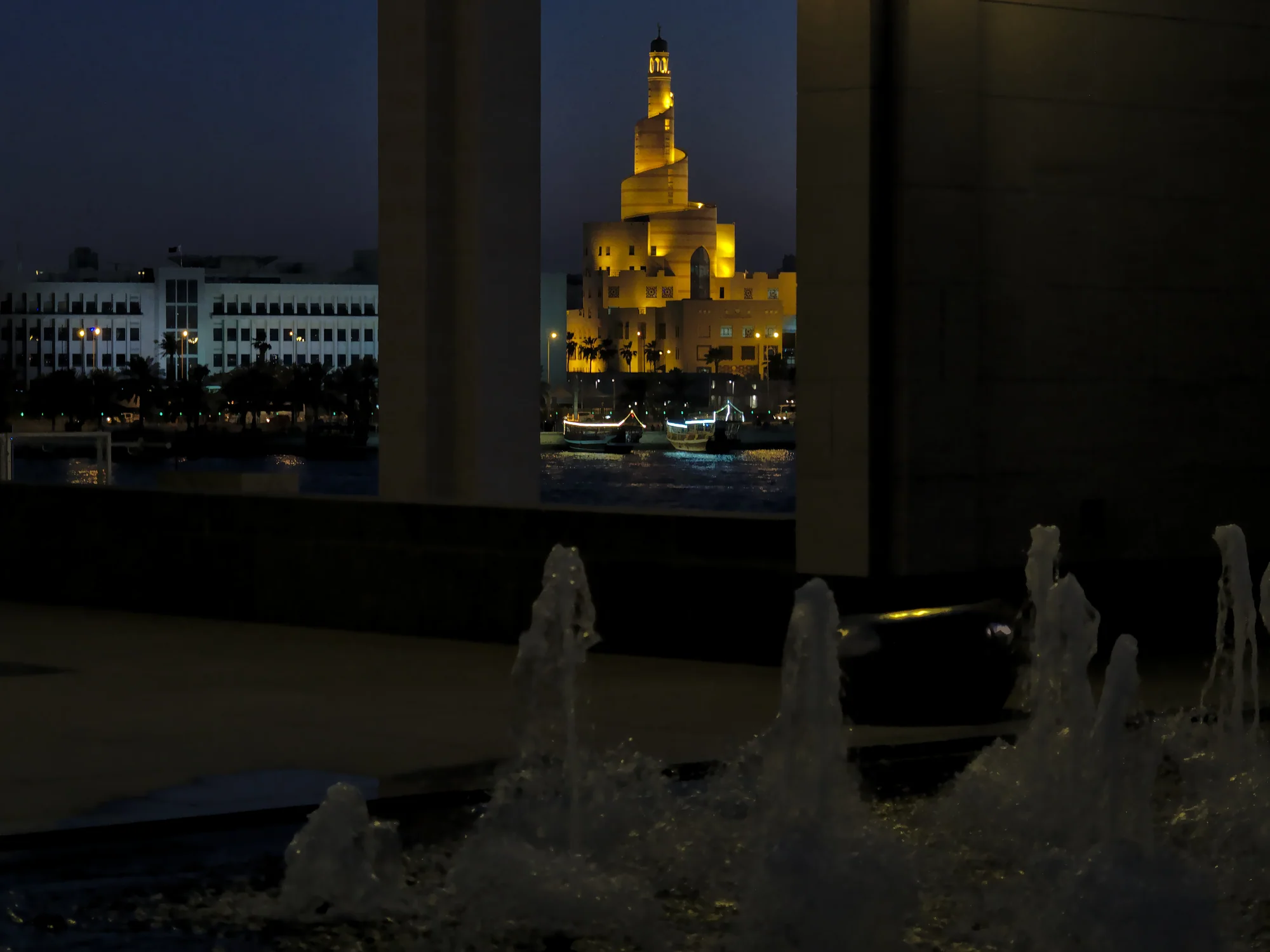 A geometric museum dome glowing gold at night above dark water.